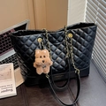 Black quilted tote bag with gold chain strap and cute bear pendant in a modern office setting - Black with Pendant
