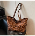 Detailansicht der Leopard-Tragetasche mit braunen Trägern und Lederanhänger auf Büchern - Braun