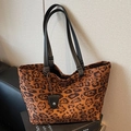 Stilvolle Leopard-Tragetasche mit schwarzen Henkeln auf modernem, minimalistischem Buch - Schwarz
