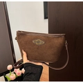 Detail der braunen Wildledertasche mit goldener Logoplakette und feiner Textur - Kaffeebraun
