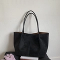 Detalle macro del bolso tote de ante negro con costuras verticales minimalistas - Negro