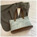 Close-up of a blue washed canvas tote bag with brown leather handles on a white background - Blue