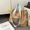 Detail of tan drawstring tote bag with light blue straps and mesh pocket on canvas books - Khaki