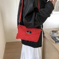 Red suede crossbody envelope bag with silver buckle worn by a model in black leather jacket - Red