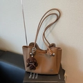 Bruine getextureerde lederen emmertas met pluche puppy-hanger en metalen logo - Khaki Met Hanger