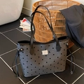 Borsa tote grigia con pois neri, fiocchi stampati e manici in pelle in un contesto reale - Nero