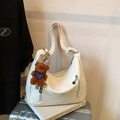 Borsa tote bianca in ecopelle con cerniere e ciondolo orsetto marrone su una valigia - Bianco con ciondolo