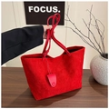 Dettaglio della borsa tote rossa in pelle scamosciata con manici e ciondolo tondo - Rosso