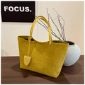 Dettaglio della borsa tote in pelle scamosciata color zenzero su tavolo in legno - Giallo