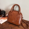 Brown leather crossbody bag with square stitching and silver logo in a stylish setting - Brown