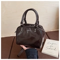 Close-up of a retro brown glossy leather Boston bag with silver rivets and metal logo - Brown