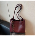 Dettaglio di una borsa tote bordeaux con trama intrecciata e logo dorato della marca - Rosso Vino Con Pendente