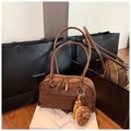 Close-up of brown suede Boston bag with a creative donut pendant and gold zipper detail - With Charm / Brown