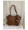 Detail of vintage brown leather tote bag with plush bear charm on white sofa - With Pendant / Brown
