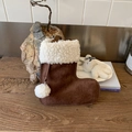 Detailed view of a brown felt Christmas stocking with white fleece trim on wood surface - Brown