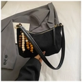 Détail d'un sac noir avec charm en perles de bois unique et fermeture éclair dorée - Noir avec pendentif