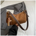 Gros plan détaillé du sac en daim marron avec gland perlé vintage et accessoires métalliques - Marron avec pendentif