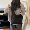 Minimalist black tote bag with wide straps and silver ring detail worn over the shoulder - Black