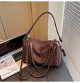 Détail d'un sac Boston en daim marron foncé avec poignées en cuir sur un bureau - Marron