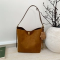 Braune Wildleder-Eimertasche mit Goldschnalle und Stern-Anhänger auf einem Tisch - Braun mit Anhänger