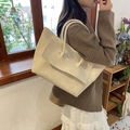 Cream textured leather tote bag with layered flap design shown on model in cafe - Off White