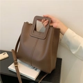 Minimalist dark brown leather bucket bag with unique cutout handles and crossbody strap - Brown