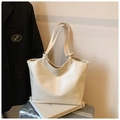 Close-up of off-white faux leather tote bag with soft texture on a silver suitcase - White