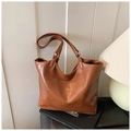 Close-up of caramel brown tote bag showing pebbled leather texture and brand logo - Brown