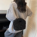 Crossbody black faux fur cylinder bag with thin strap worn by model in gray sweater - Black