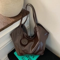Borsa a secchiello in pelle lucida marrone scuro con ciondolo rotondo e doppi spallacci - Marrone