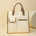 Close-up of canvas tote bag featuring functional front pockets and brown fabric handles - Off White