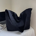 Bolso tote grande negro minimalista de nailon con correa ancha en un espacio de trabajo - Negro
