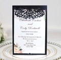 Macro view of laser-cut filigree invitation cover with printed wedding card details - Black