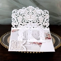 Macro detail of laser-cut wedding invitation featuring white arch and floral inner card - White