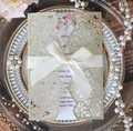Detail of laser cut glitter gold wedding invitation with white ribbon and floral insert - Light Gold Glitter