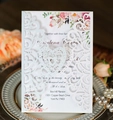 Détail de l'invitation de mariage découpée au laser avec cœur et motif floral - Blanc