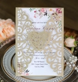 Detail of laser-cut gold wedding invitation with floral insert on a dinner plate - Beige Gold