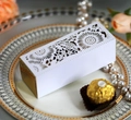 Detailed view of laser-cut wedding candy box with elegant floral patterns on a gold base - White