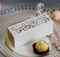 Macro detail of laser-cut wedding favor box with elegant floral patterns on white and gold card - Ivory