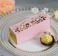 Macro shot of laser-cut pink and gold hollow wedding favor box with floral patterns - Pink