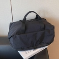 Black waterproof nylon travel bag with dual handles and large capacity on leather chair - Black
