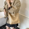 Primer plano del bolso saco de tejido dorado con textura de cuero y etiqueta de la marca - Dorado