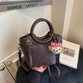 Dunkelbraune Lederbeuteltasche mit Griff, goldener Hardware und Plüschtier-Anhänger - Kaffeebraun