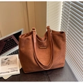 Detailed macro view of large brown suede tote bag with golden metal bar on black surface - Brown