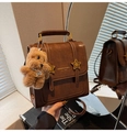 Detailed view of a vintage brown leather bag with star hardware and plush dog charm - With Charm / Brown