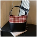 Détail du sac seau à carreaux rouge et blanc avec base en cuir noir sur bois - Rouge