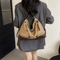 Khaki canvas emmer rugzak met bruin lederen details gedragen door een model in een pak - Khaki