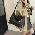 Large black and brown bucket bag with decorative zippers shown on a model crossbody - Black