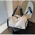 Detail einer großen weißen Reisetasche mit schwarzen Riemen und Logo am Kleiderbügel - Cremeweiß