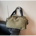 Detail der olivgrünen Reisetasche mit Doppelgriffen, Gurt und strukturiertem Hintergrund - Grün